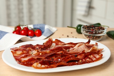 Photo of Slices of tasty fried bacon on wooden table indoors