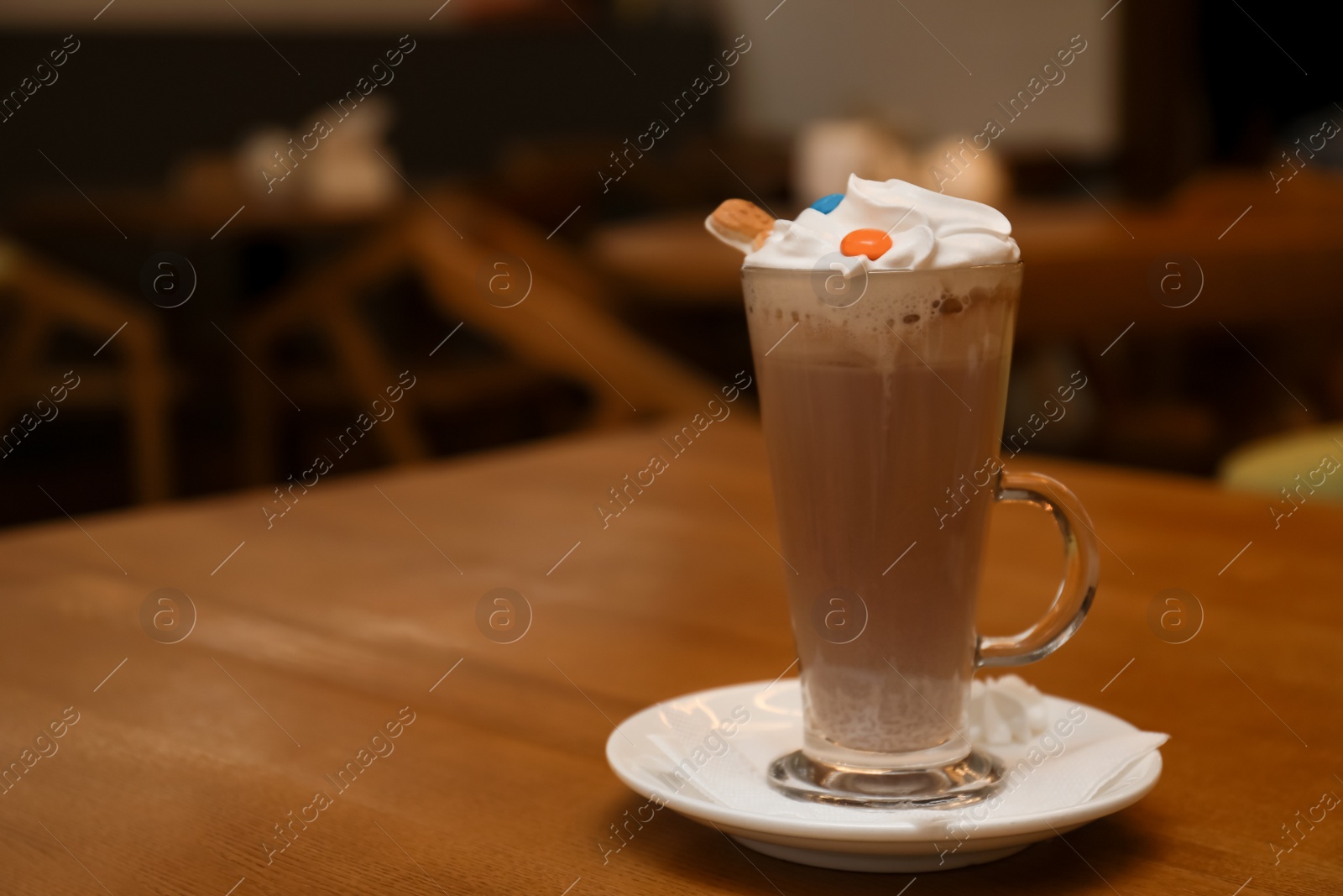 Photo of Cup of aromatic cacao on table against blurred background. Space for text