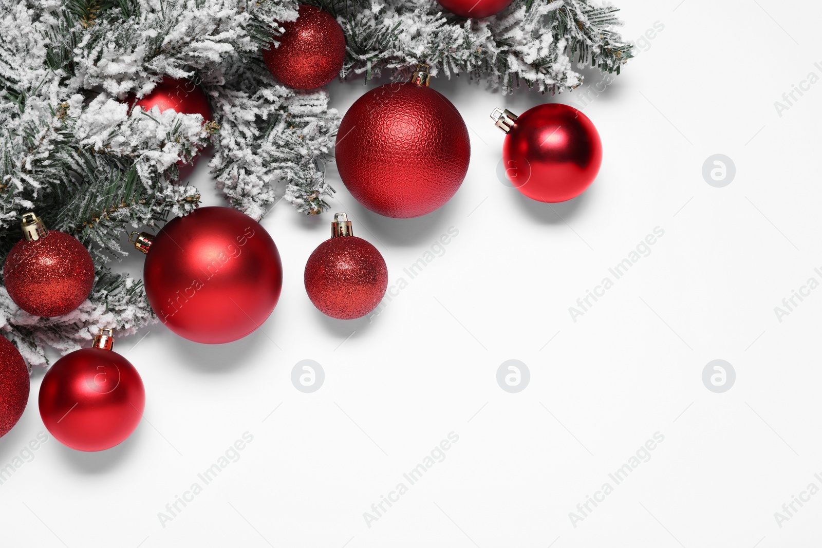 Photo of Shiny red Christmas balls and fir tree branches with snow on white background, flat lay. Space for text