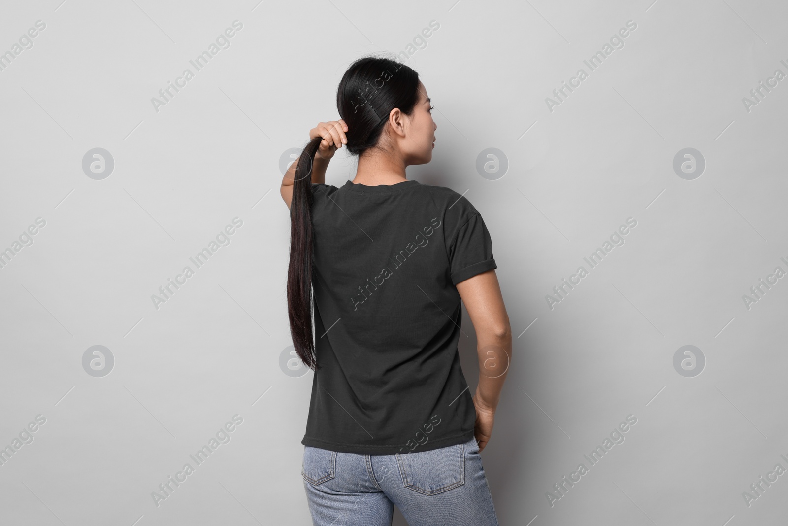 Photo of Woman wearing black t-shirt on light grey background