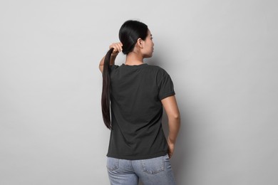 Woman wearing black t-shirt on light grey background