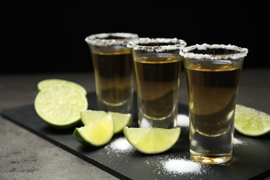 Photo of Mexican Tequila shots with salt and lime on grey table