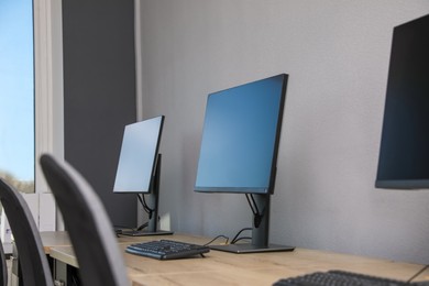 Open office interior. Modern workplaces with computers near light grey wall