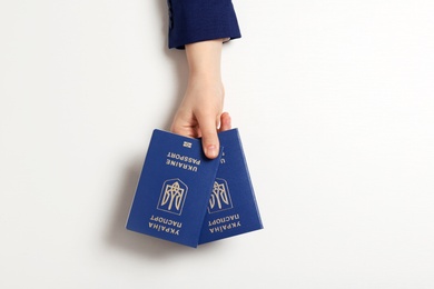 Photo of Woman holding Ukrainian travel passports on light background, top view. International relationships