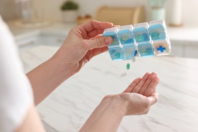 Photo of Woman with pills and organizer at white marble table, closeup