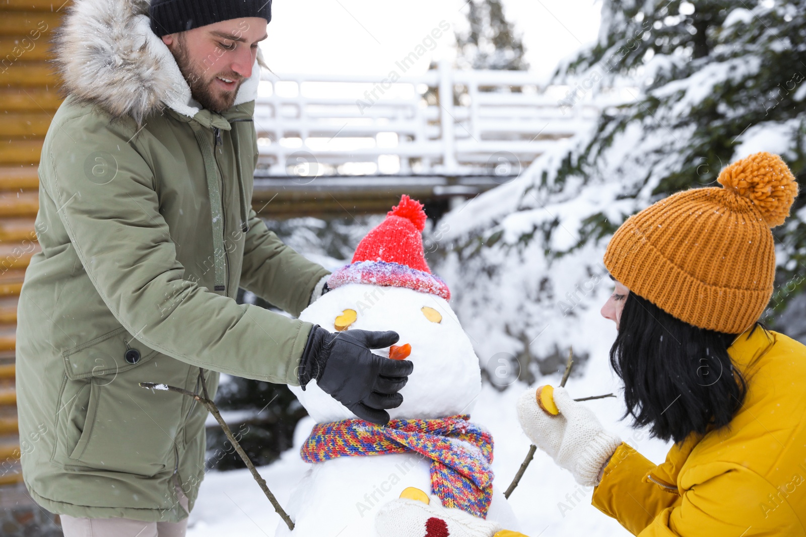 Photo of Happy couple making snowman outdoors. Winter vacation