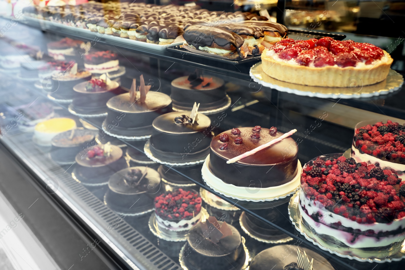 Photo of Different delicious cakes on display in cafe, view through window