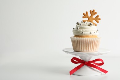 Photo of Tasty Christmas cupcake with cream and snowflake cookie on white background, space for text