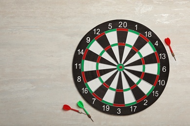 Dart board with color arrows on light stone background, top view. Space for text