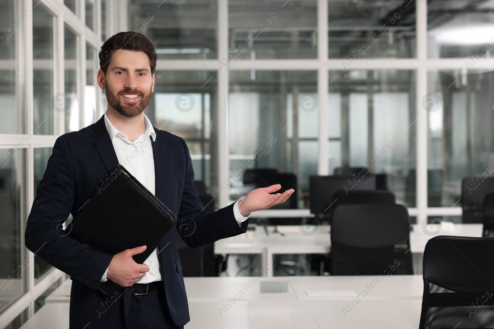 Photo of Happy real estate agent with leather portfolio indoors. Space for text