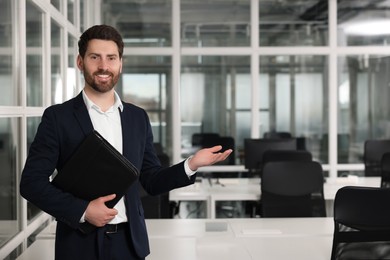 Photo of Happy real estate agent with leather portfolio indoors. Space for text