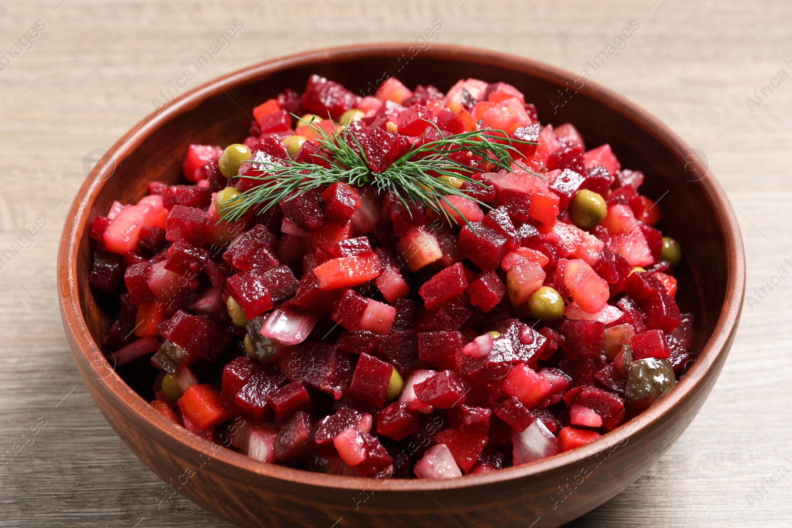 Photo of Bowl of delicious fresh vinaigrette salad on wooden table, closeup