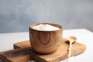 Photo of Wooden bowl with creamy yogurt served on table