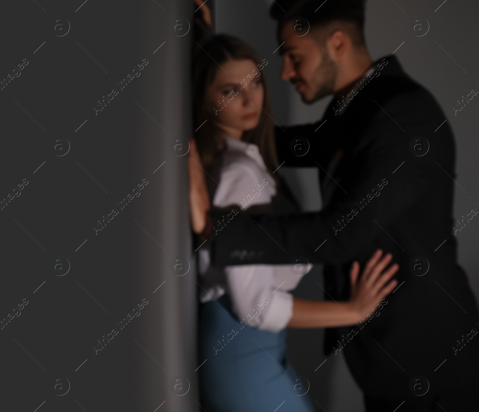 Photo of Boss molesting his female secretary on dark background. Sexual harassment at work