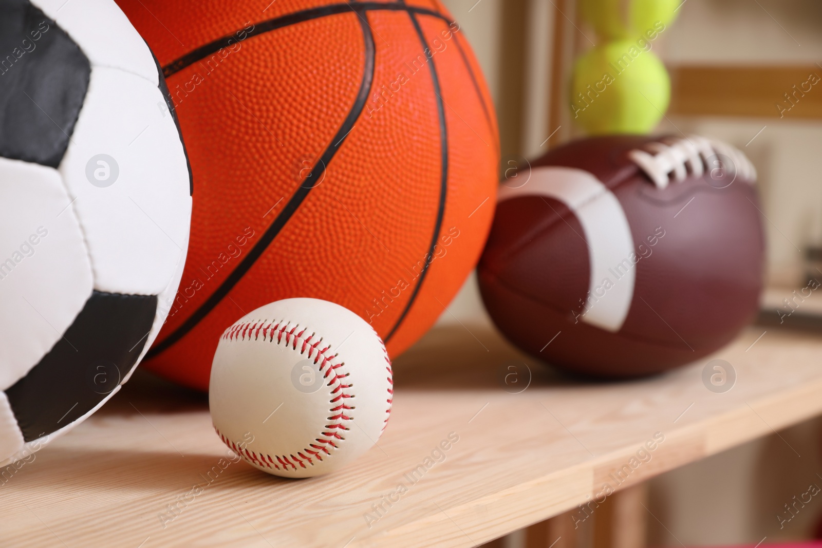 Photo of Different sport balls on wooden shelf, closeup