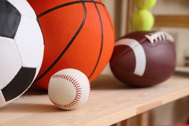 Different sport balls on wooden shelf, closeup