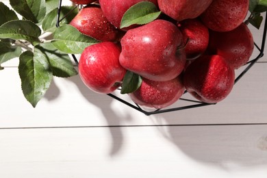 Photo of Ripe red apples with water drops and green leaves on white wooden table, flat lay