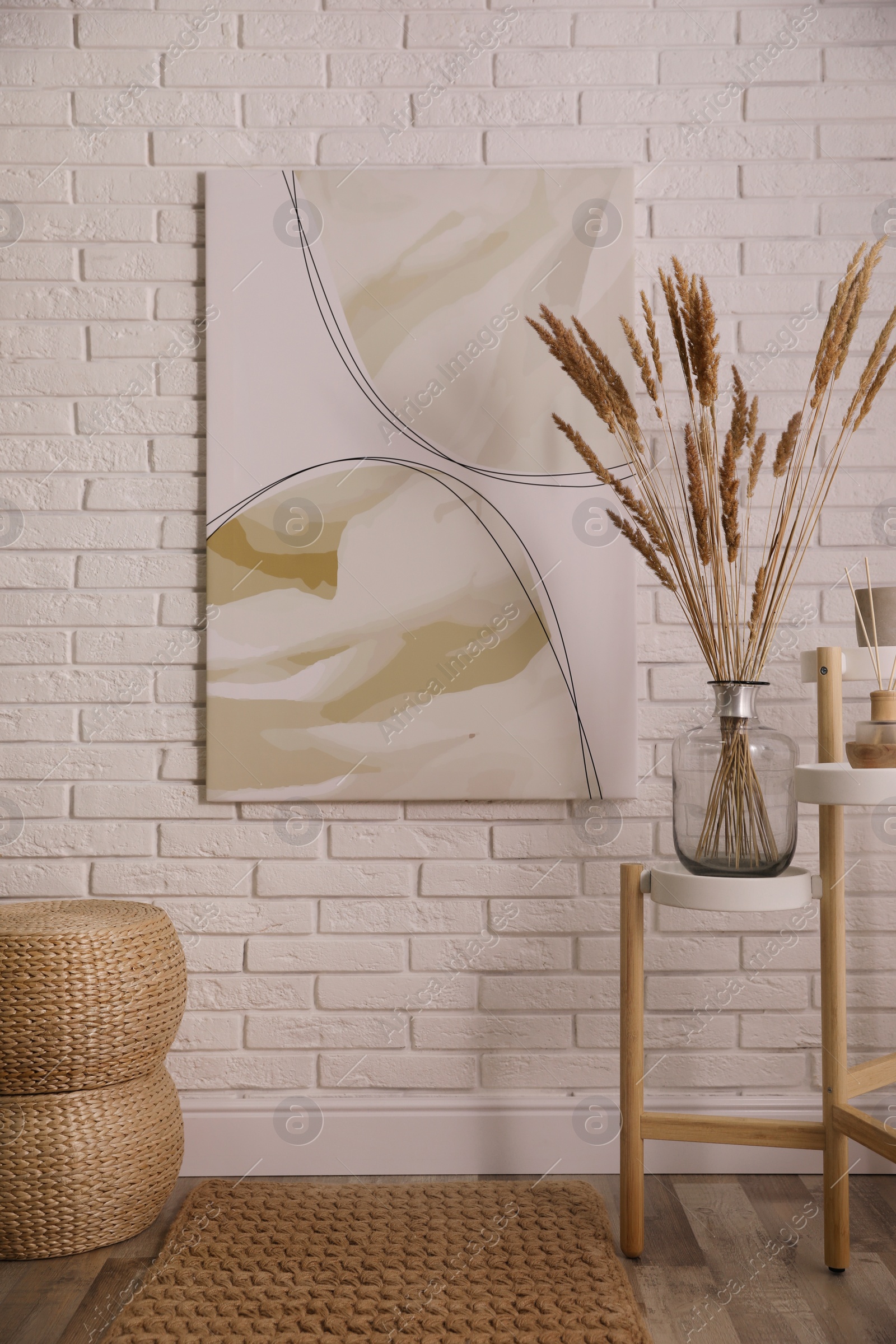 Photo of Fluffy reed plumes and painting in stylish room interior