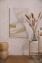 Fluffy reed plumes and painting in stylish room interior