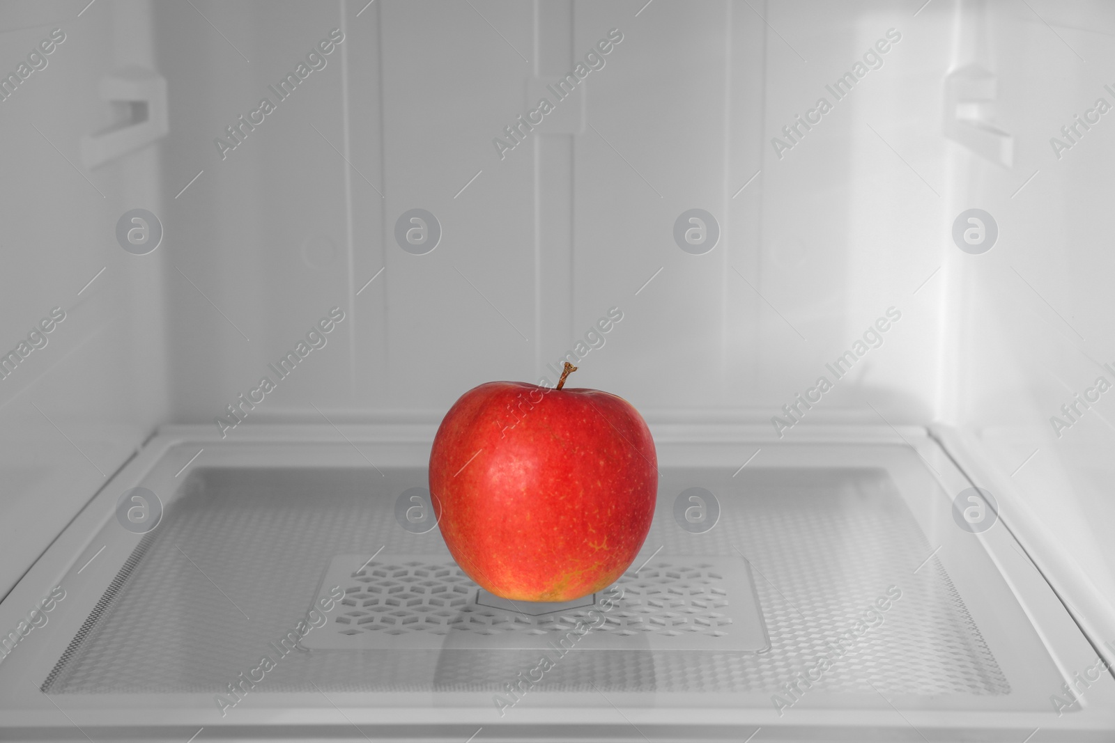 Photo of Red apple on shelf inside modern refrigerator