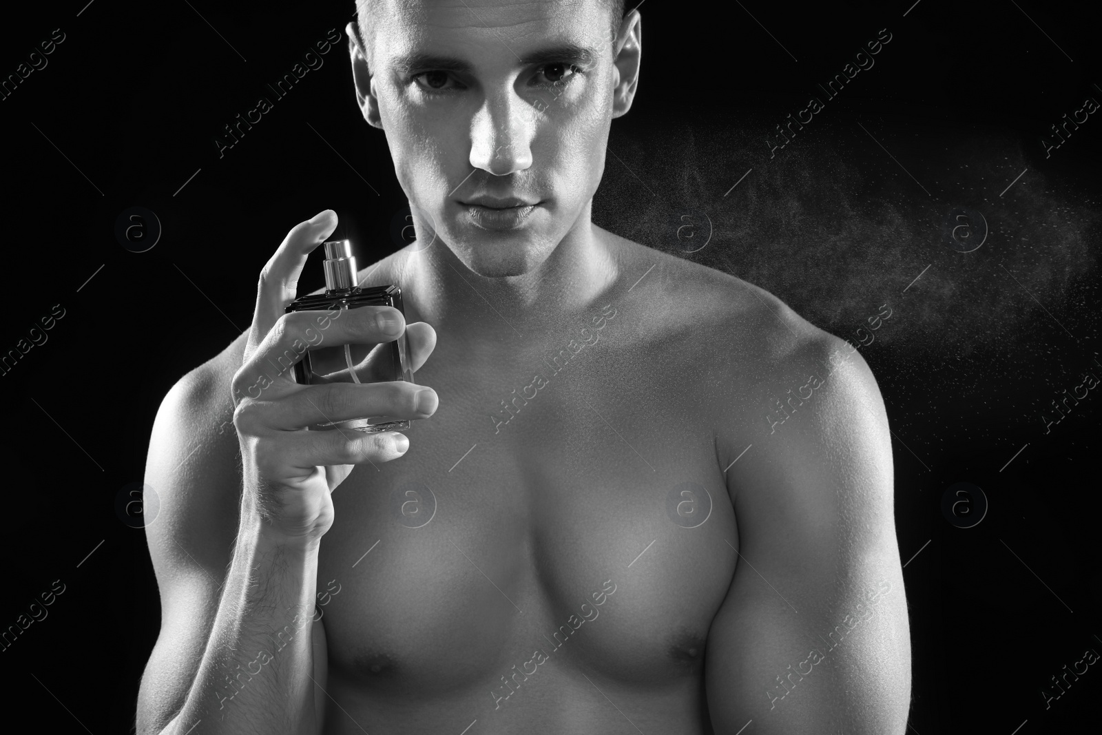 Photo of Handsome young man spraying perfume, black and white effect