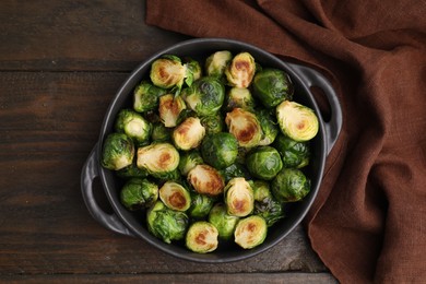 Photo of Delicious roasted Brussels sprouts in baking dish on wooden table, top view