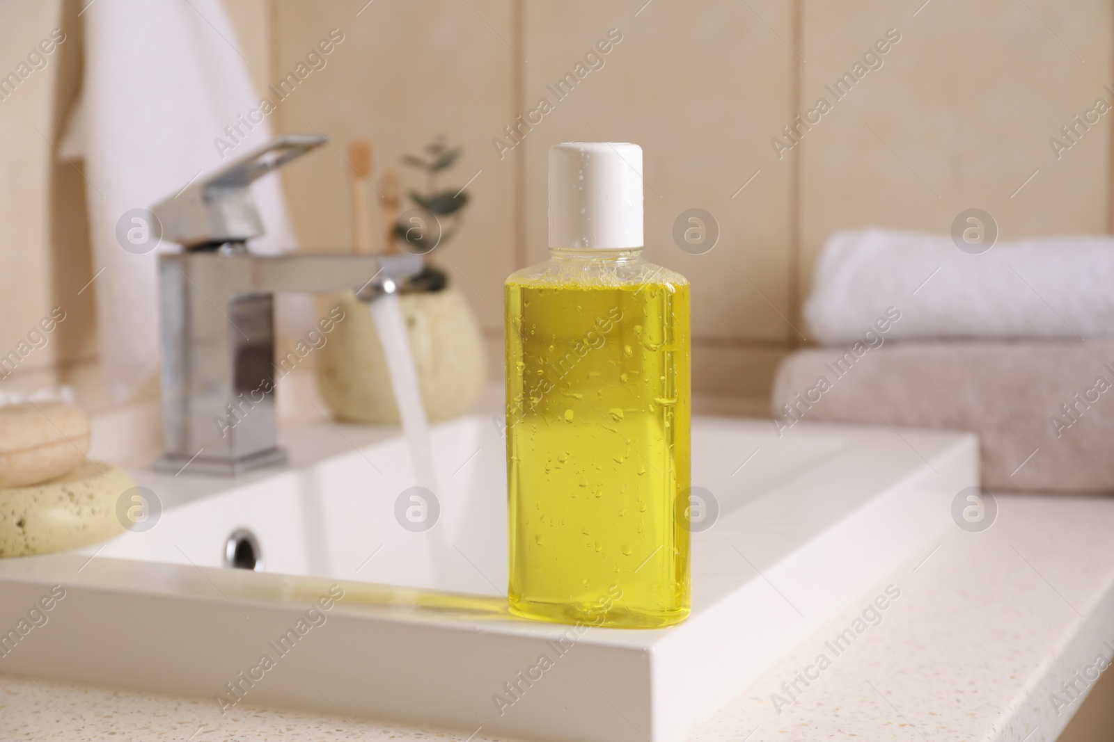 Photo of Fresh mouthwash in bottle on sink in bathroom, closeup