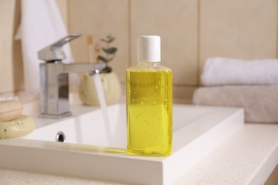 Fresh mouthwash in bottle on sink in bathroom, closeup