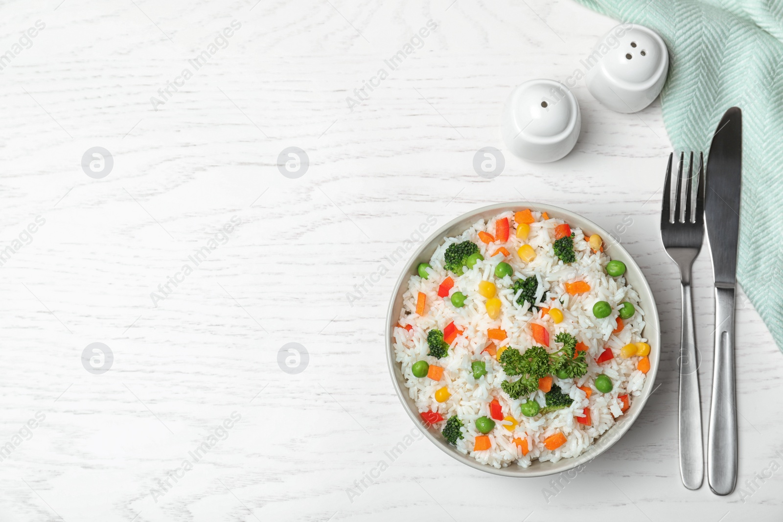 Photo of Bowl with tasty rice and vegetables on wooden background, flat lay. Space for text