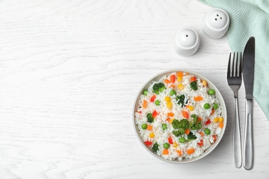 Photo of Bowl with tasty rice and vegetables on wooden background, flat lay. Space for text