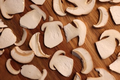 Photo of Slices of mushrooms on wooden board prepared for natural dehydration, closeup