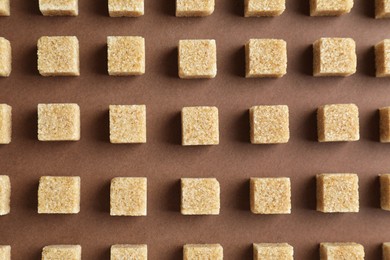 Photo of Brown sugar cubes on color background, top view