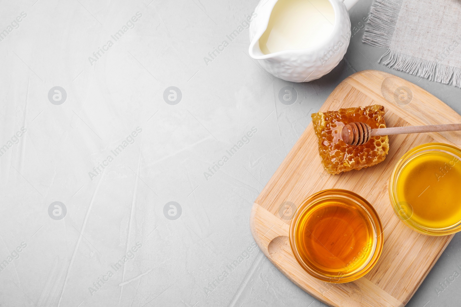 Photo of Flat lay composition with tasty honey on light grey table, space for text