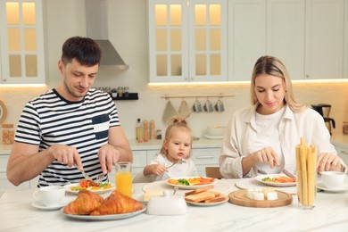 Happy family having breakfast together at table in kitchen