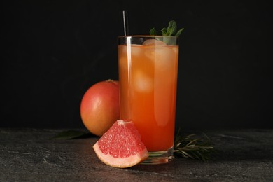 Photo of Tasty grapefruit drink with ice and mint in glass on dark textured table