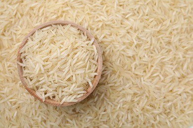 Bowl and raw rice as background, top view. Space for text