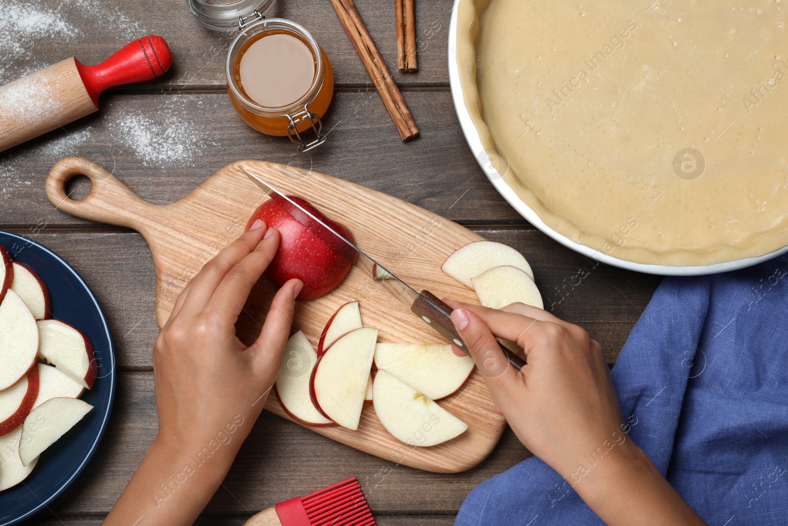 Photo of Woman cutting apple at wooden table, top view. Baking pie