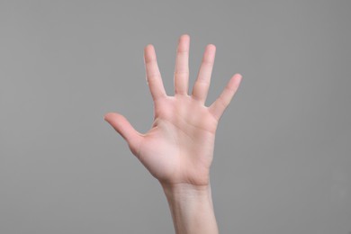 Photo of Woman giving high five on grey background, closeup
