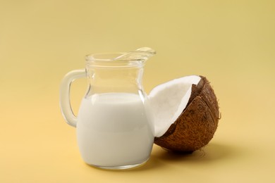 Photo of Glass jug of delicious vegan milk and coconut on yellow background