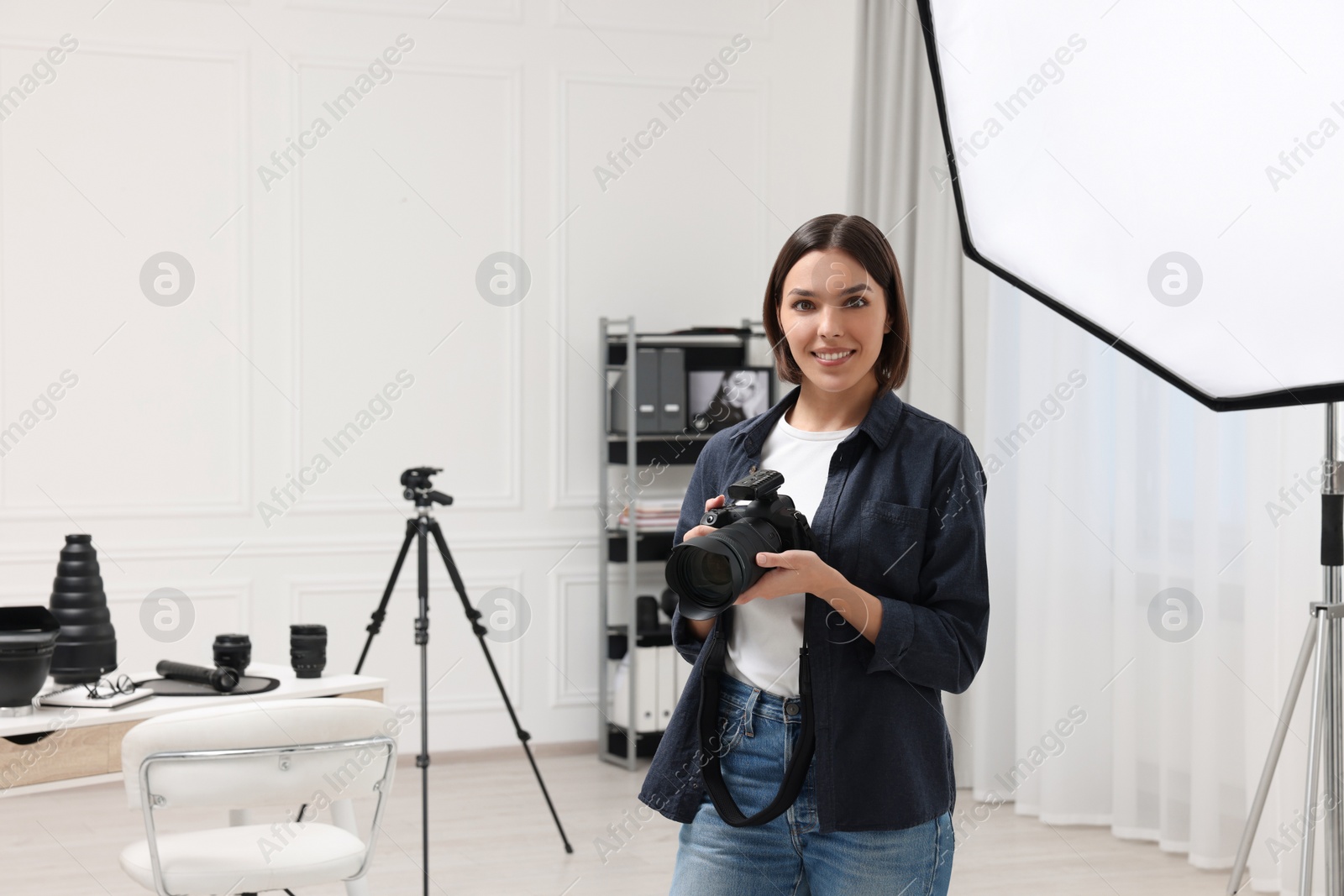 Photo of Young professional photographer with camera in modern photo studio, space for text