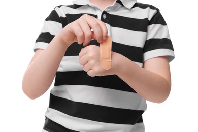 Photo of Little boy putting sticking plaster onto hand on white background, closeup