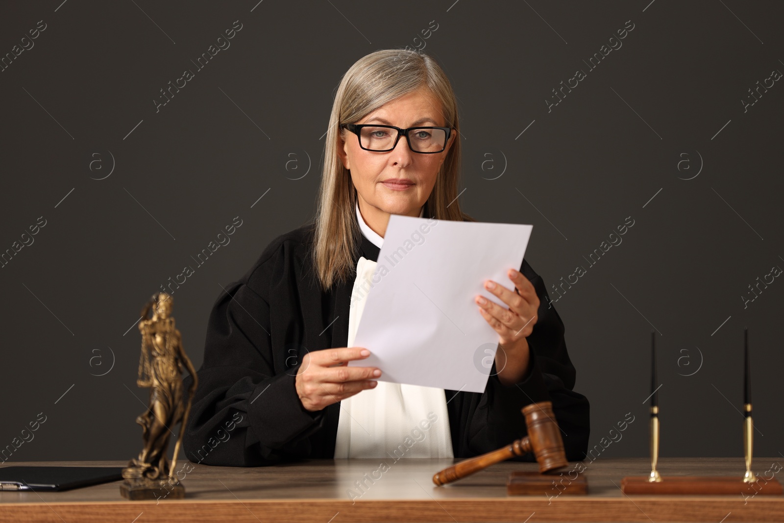 Photo of Judge in court dress working with document indoors