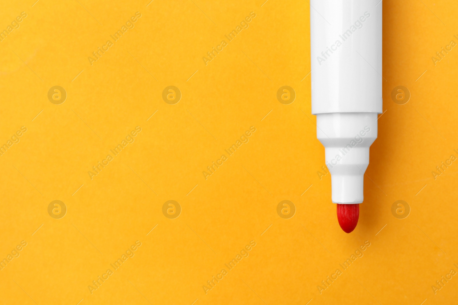 Photo of Bright red marker on orange background, top view. Space for text