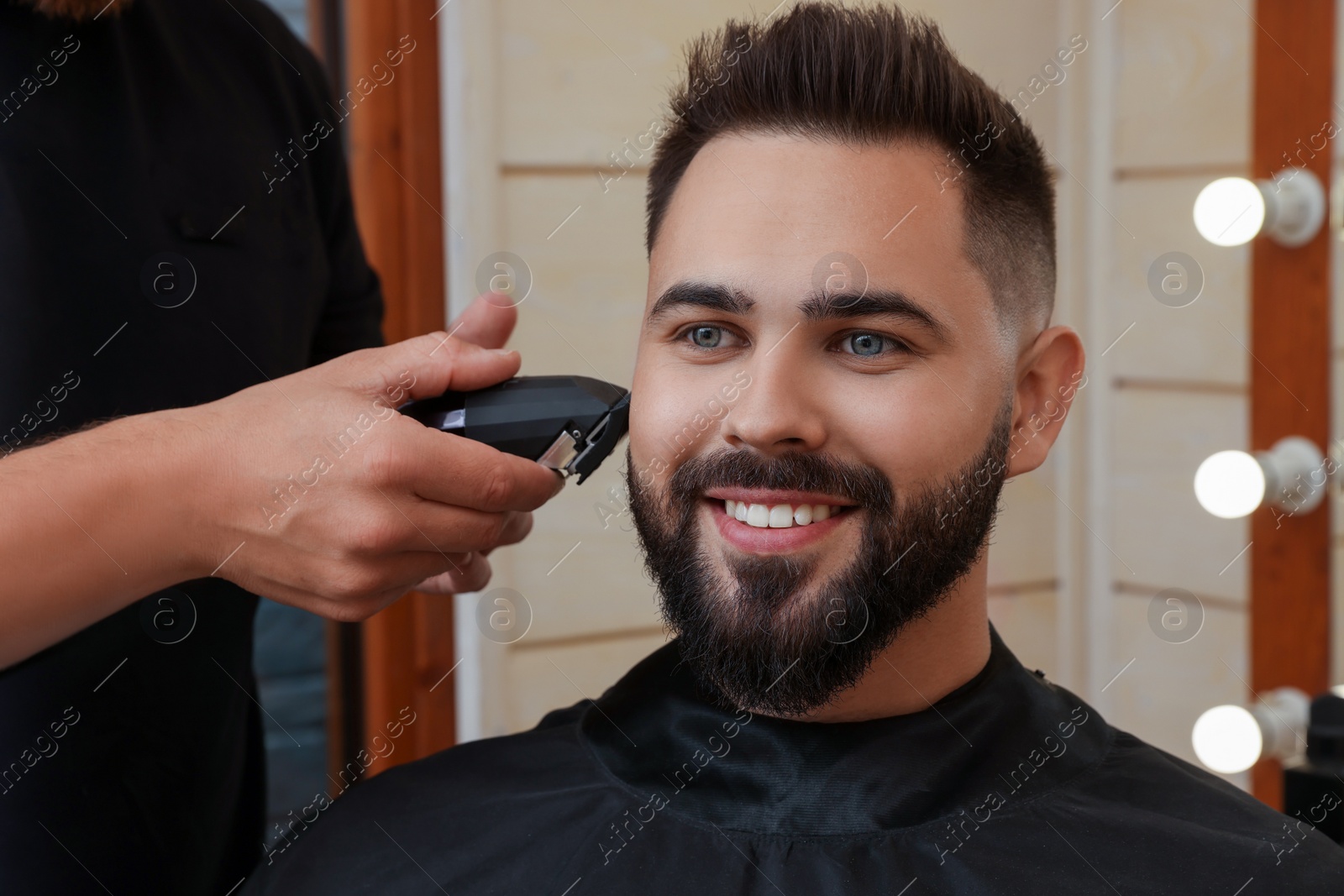 Photo of Professional hairdresser working with client in barbershop, closeup