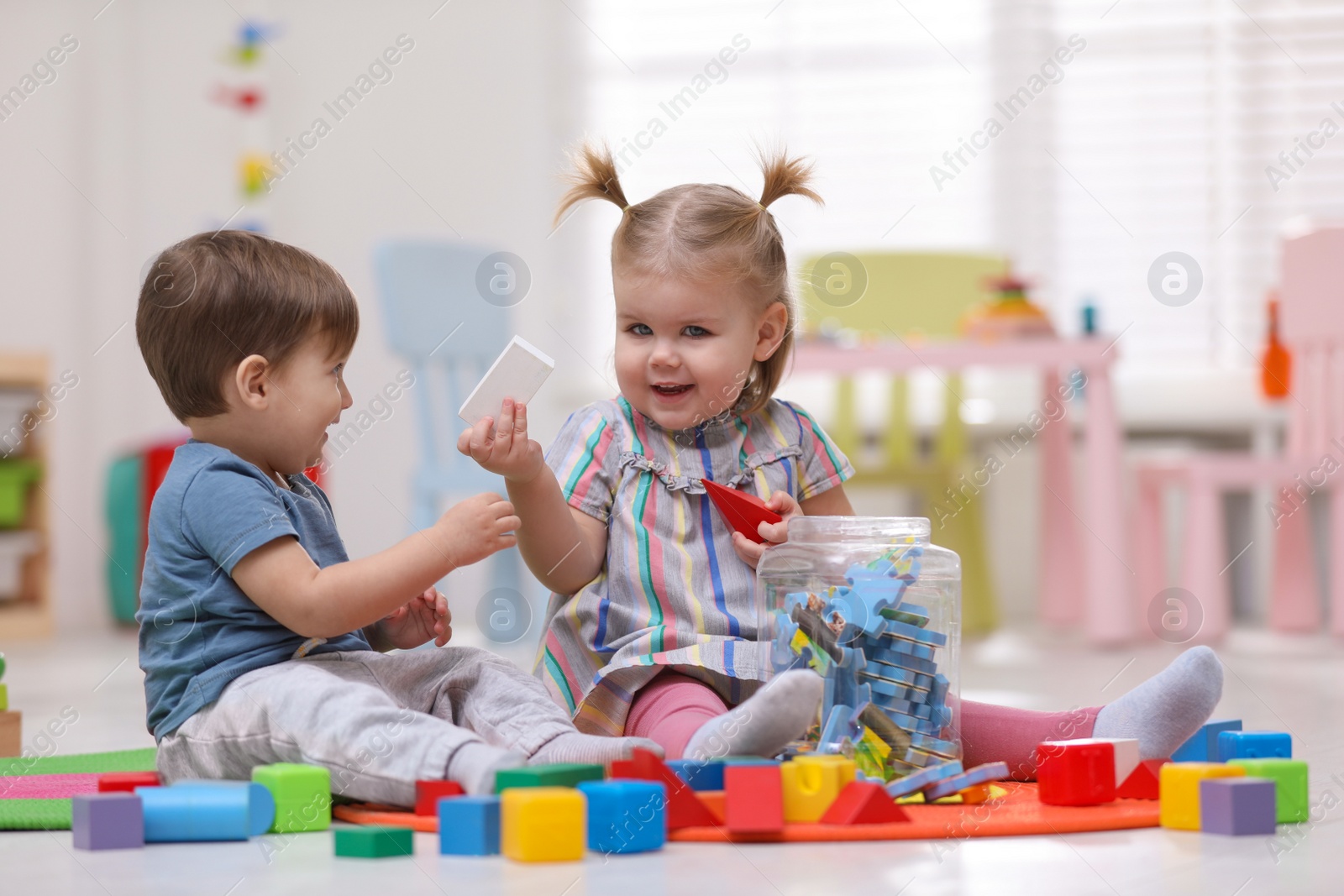 Photo of Cute little children playing together on floor at home