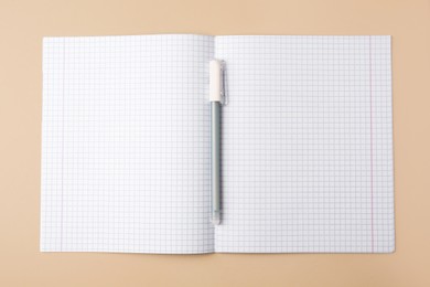 Photo of Copybook with erasable pen on beige background, top view