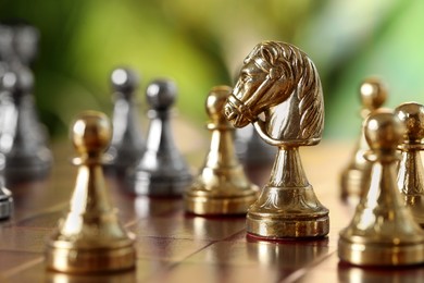 Golden chess pieces on game board against blurred background, closeup. Space for text