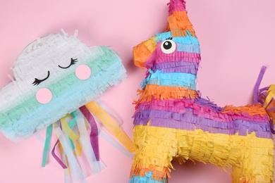 Different bright pinatas on pink background, flat lay
