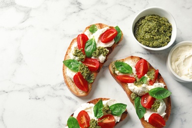 Toasted bread with tasty cream cheese and tomatoes on marble table, flat lay. Space for text