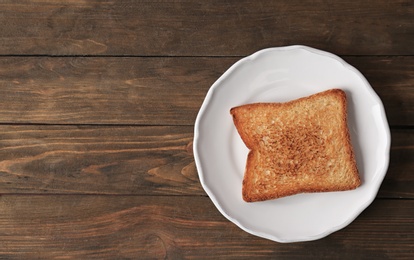 Plate with toasted bread on wooden background, top view